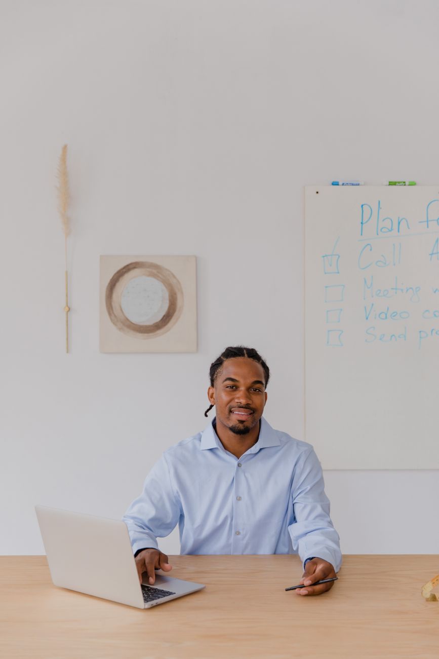Professional man working at a desk in office with laptop and whiteboard.